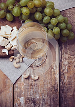 Glass of white wine, grapes, cashew nuts and soft cheese