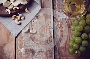 Glass of white wine, grapes, cashew nuts and soft cheese