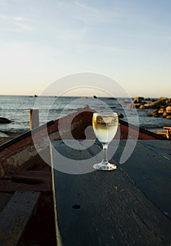 Glass of white wine on the old boat at sunset, selective focus