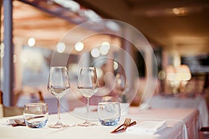 A glass of white wine on a table in a restaurant. Toned photo. Glare and light spots. Free space for text.
