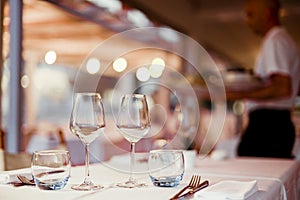 A glass of white wine on a table in a restaurant. Toned photo. Glare and light spots. Free space for text.