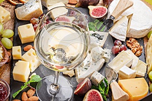 Glass of white wine with variety of sliced cheeses