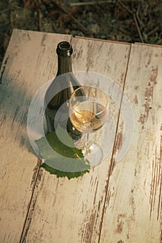 Glass with white wine in vineyard on old table