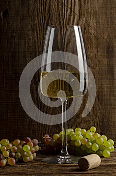 Glass of white wine on vintage wooden background. Vertical