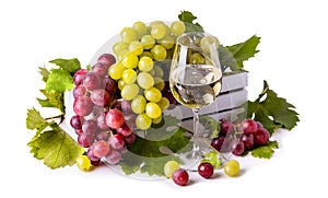 Glass of white wine, White and pink grapes with green leaves in a white wooden box.