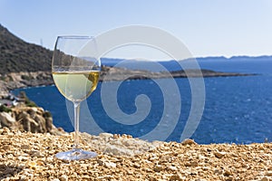 A glass of white wine. Wine against the backdrop of the sea coast and a sunny summer beach. Wine tasting and relaxation at the