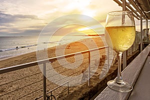 Glass of white wine on a wooden bench overlooking the beach with