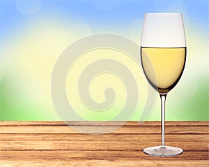 Glass of white wine on wooden table over nature background