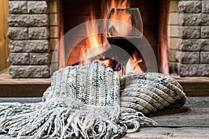 Glass of wine against cozy fireplace background, hygge concept