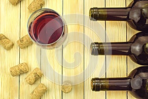 Glass of wine on background of bottles and corks