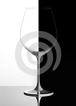 Glass of wine on a black and white background, with reflection. Domino concept