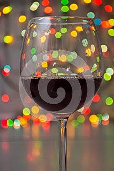 Glass of wine on garland christmas colourful background