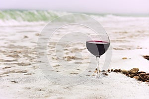 Glass of wine in the foam of the sea on the shore