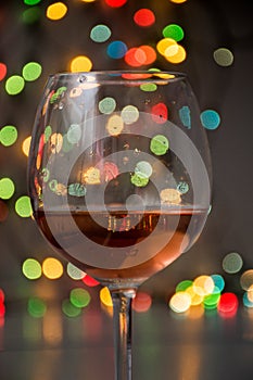 Glass of wine on garland christmas colourful background