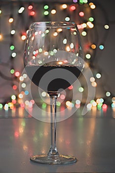 Glass of wine on garland christmas colourful background