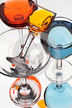Glass wine glasses with multicolored liquid on a white background