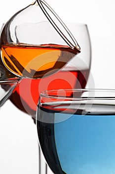 Glass wine glasses with multicolored liquid on a white background