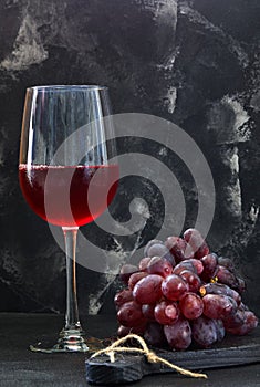 Glass of wine with grapes on a black wooden stand