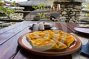 Glass of wine and hot placinta on a wooden table