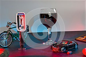 A glass of wine near toy wrecked auto, space for text. Dangerous drinking and driving