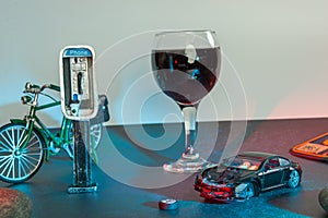 A glass of wine near toy wrecked auto, space for text. Dangerous drinking and driving