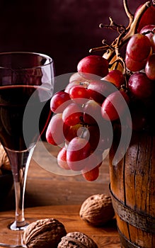 A glass of wine and red grapes on barrel