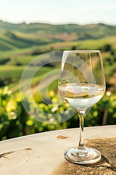 A glass of wine is sitting on a table in front of a beautiful landscape