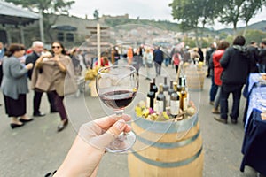 Glass of wine at tasting area of annual city festival Tbilisoba with crowd of people around. Tbilisi, Georgia country