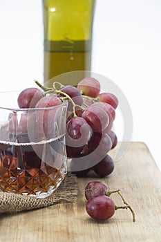 glass of wine and wine bottle with grapes isolated on wooden background