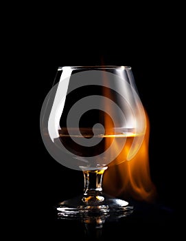 Glass of wisky in fire flame on black background