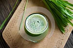 A glass of young barley grass juice with fresh blades