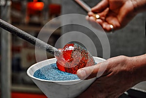 Glassblower applying frit to molten glass