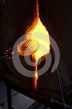 Glassblower shaping molten glass in a kiln