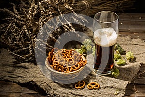 Glasse beer with wheat and hops, basket of pretzels