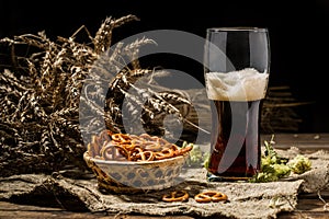 Glasse beer with wheat and hops, basket of pretzels