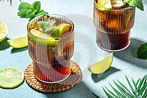 Glasses of Alcohol cocktail cuba libre with rum, cola, mint and lime in the glass on a light background, place for text