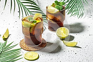 Glasses of Alcohol cocktail cuba libre with rum, cola, mint and lime in the glass on a light background, place for text