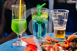 Glasses with alcoholic cocktails and a glass with beer on the table outdoors