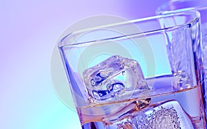 Glasses of alcoholic drink cocktail with ice on disco blue light