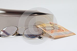 Glasses on the background of a thick book and euro banknotes, secured old age