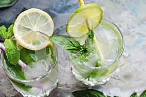 Glasses of basil lemonade with ice, lemon and lime