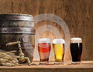 Glasses of beer and ale barrel on the wooden table.