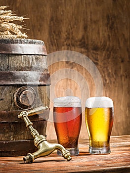 Glasses of beer and ale barrel on the wooden table.