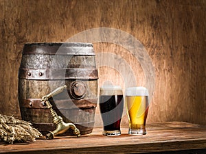 Glasses of beer and ale barrel on the wooden table.