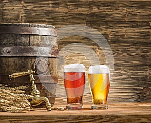 Glasses of beer and ale barrel on the wooden table.