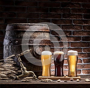 Glasses of beer and ale barrel on the wooden table. Craft brewer