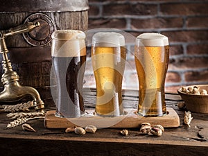 Glasses of beer and ale barrel on the wooden table. Craft brewery