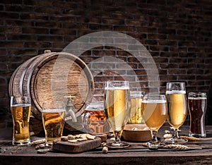 Glasses of beer and ale barrel on the wooden table. Craft brewery