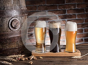 Glasses of beer and ale barrel on the wooden table. Craft brewery