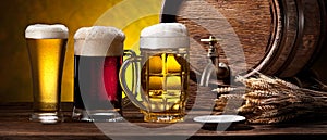 Glasses of beer and beer cask on the wooden table. Craft brewery photo
